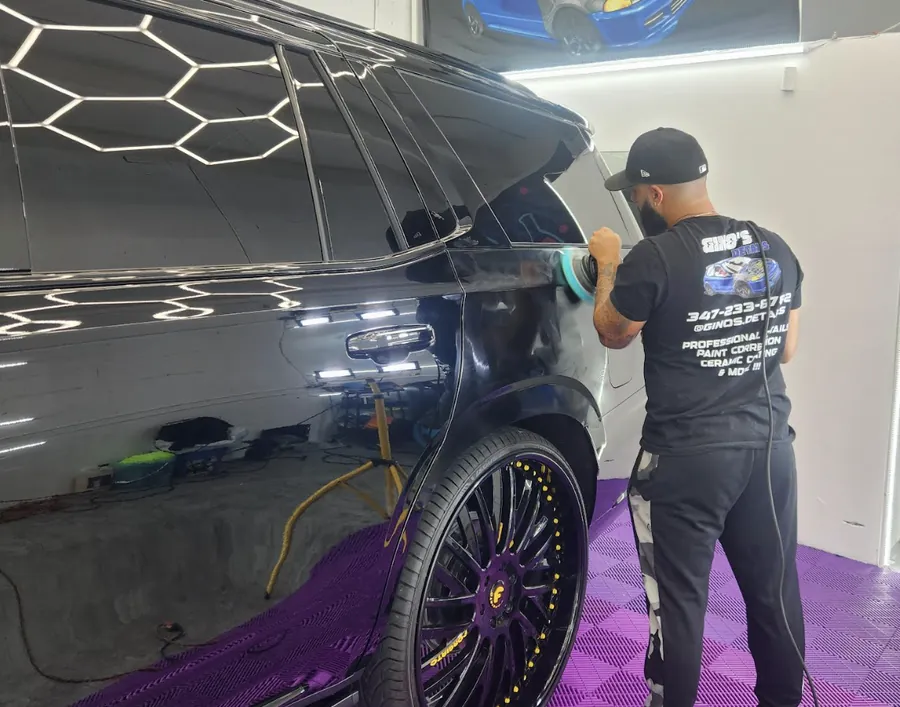 Gino machine-polishing a black SUV in the shop