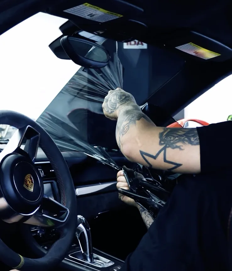 Installer applying tint from inside a Porsche